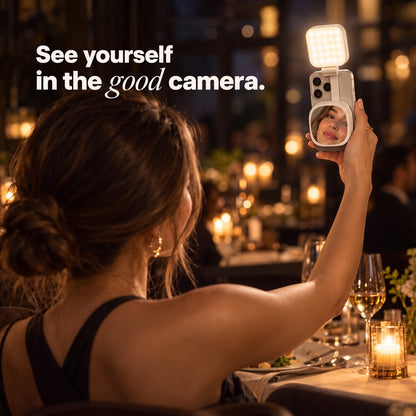 A woman at a restaurant table sees her face in the Studio mirror while shooting with her back camera
